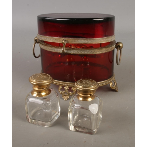 4 - An antique ruby glass two bottle perfume casket featuring cut glass bottles, ornate brass mounts and... 