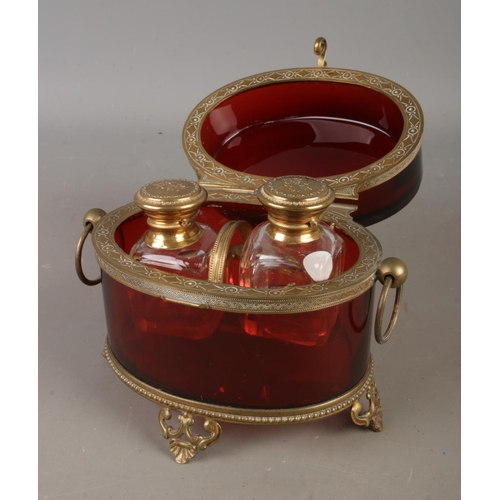 4 - An antique ruby glass two bottle perfume casket featuring cut glass bottles, ornate brass mounts and... 
