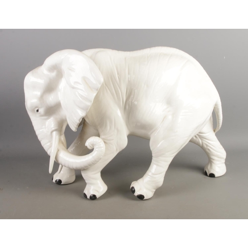 74 - A large white Italian ceramic model of an elephant, together with a leather wrapped model of a camel... 