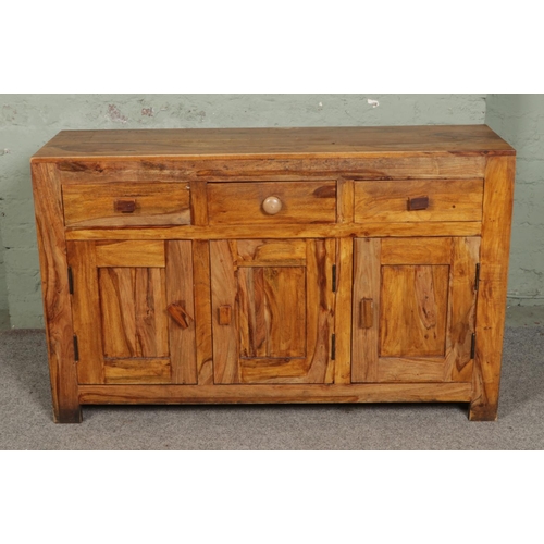 539 - A contemporary mango wood sideboard with three upper drawers and three cupboards below. L131cm.