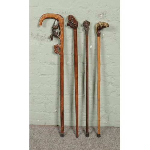 174 - Four vintage novelty handled walking sticks; Featuring a carved dog hunting a rabbit, a composite wo... 