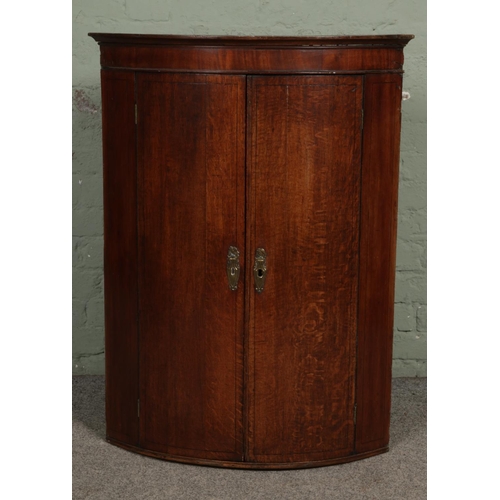 421 - An oak bow fronted corner cupboard; Internal shelves. H102cm.
