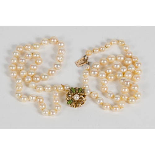 77 - A Two Strand Cultured Pearl Necklace, with a 9 carat clasp, set with green stones.