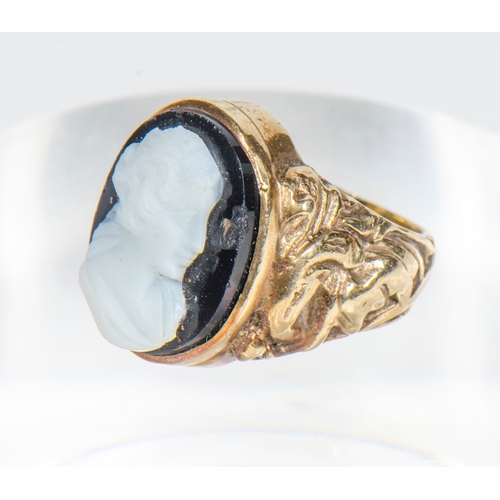 82 - A Gentleman's 9 Carat Gold Ring, set with floral decorated shoulders and agate carving of a mans hea... 