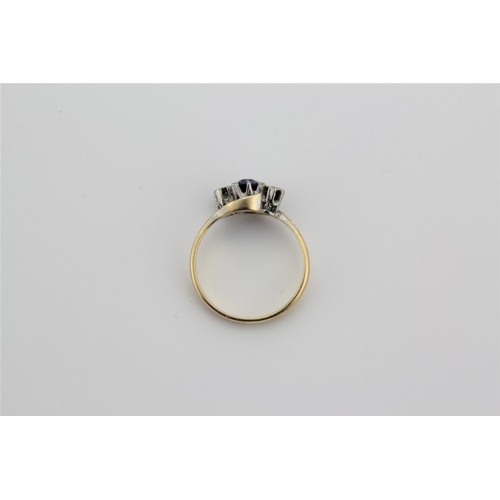 189 - A ladies 18 carat gold dress ring, set with a central sapphire and two diamonds, in a cross over set... 