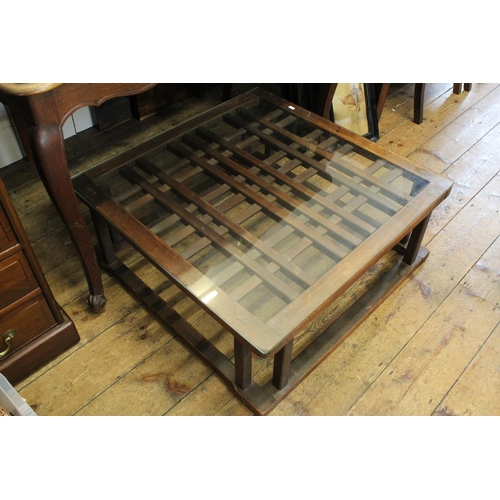 414 - A Stained Mahogany Low Down Hardwood Table with Cross Splat Decoration and Glass Top.