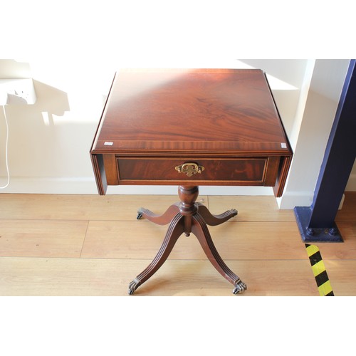 429 - A Mahogany cross banded drop flap side table resting on a pedestal base.