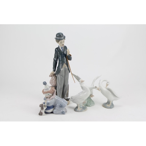 576 - A Lladro Study of Charlie Chaplin, a Study of a Clown and Three Swan Ornaments.