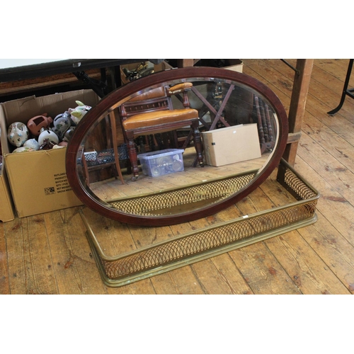 693 - A Late 19th Century pierced Brass Fender along with an Oval Mirror with Lined inlay.