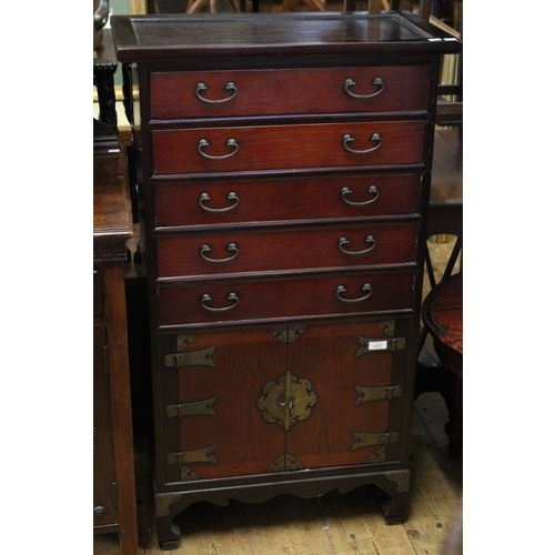 233 - An Asian hardwood narrow chest of drawers above a two door cupboard resting on shaped legs, brass ha... 