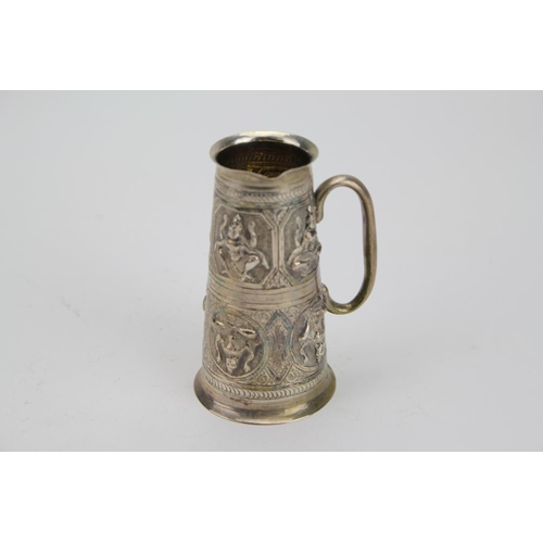 77 - An Indian Silver coloured White Metal Spirit Jigger decorated with female subjects. Weighing: 90g.