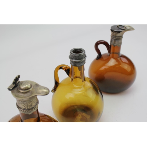 348 - 2 x Smokey Glass Claret Jugs with plated mounts along with one other pewter mounted.