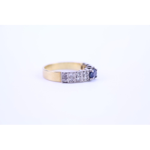 121 - A 18ct Gold dress ring set with a Sapphire and surrounding diamonds. Size approx N.