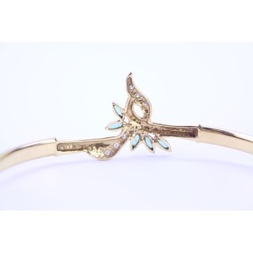 129 - An 18ct Gold ladies bangle in the floral design set with Diamonds & Emeralds. Weight approx 10g.