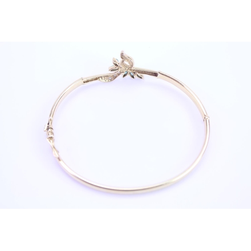 129 - An 18ct Gold ladies bangle in the floral design set with Diamonds & Emeralds. Weight approx 10g.