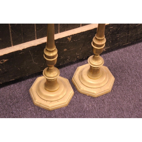 557 - A Large Pair of Turned Brass Altar Candle Sticks resting on Octagonal Bases. Measuring: 68cms high.