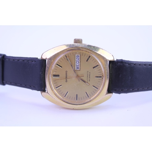 208 - A Garrard Automatic Gold Coloured Wristwatch with day/date, Gold coloured face and black leather str... 