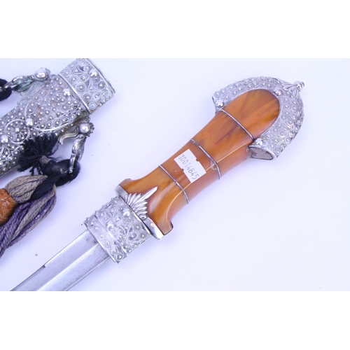 384 - A Khanjar Dagger in a Silver Coloured White Metal Filigree Sheath, Amber coloured handle, Wirework d... 