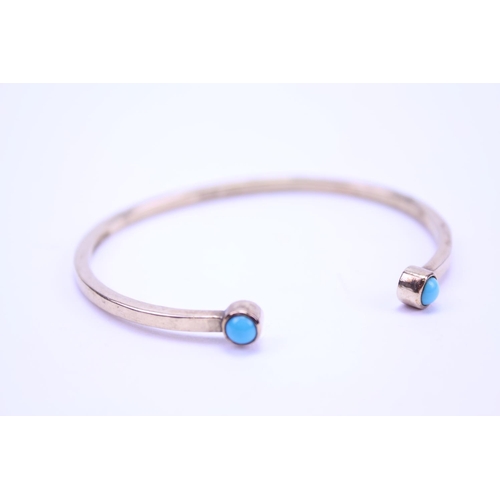 214 - A Ladies 9ct Gold Turquoise Set Bangle. Weighing: 14 grams.