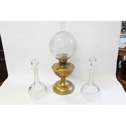 317 - Two thumb cut glass decanters along with a brass oil lamp with glass funnel and shade.