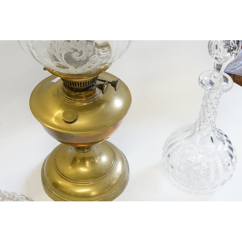 317 - Two thumb cut glass decanters along with a brass oil lamp with glass funnel and shade.