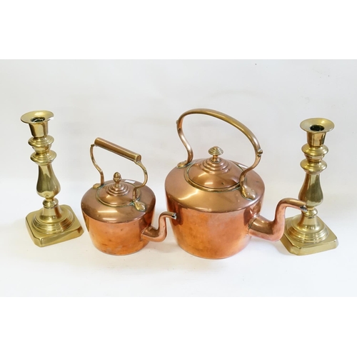 408 - Two Victorian copper kettles along with a pair of brass candlesticks.