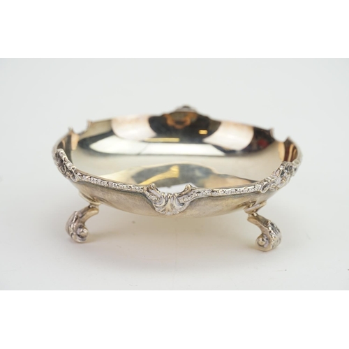 22 - A Silver Cast edged Pin Dish resting on floral swag feet. Weighing: 119 grams.