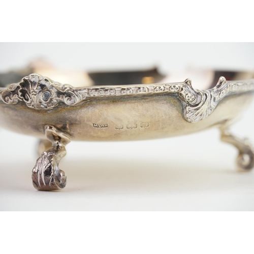 22 - A Silver Cast edged Pin Dish resting on floral swag feet. Weighing: 119 grams.