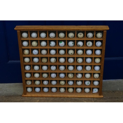 687 - A Good Collection of various Tournament Game Golf Balls displayed in a pigeon hole glazed cabinet. (... 