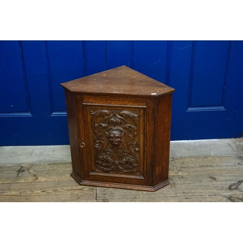 595 - A late Victorian carved oak fronted single door corner cupboard, depicting a green man and stylised ... 