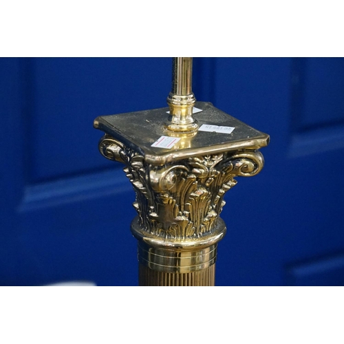 413 - A Brass Corinthian columned standard lamp resting on a gadrooned base with lion paw feet.