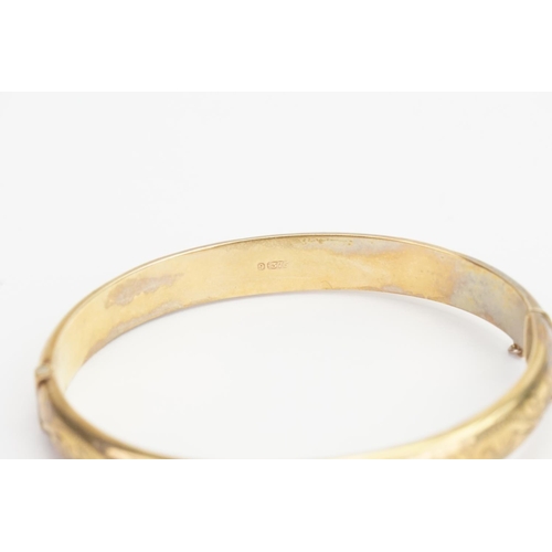 165 - A 9ct Gold engraved Bangle. Diameter: 5.5cms x 6.5cms. Weight: 11.8 grams.