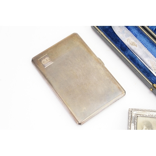 26 - A Silver cigarette case with engine turned decoration, along with a small Silver photo frame and fru... 