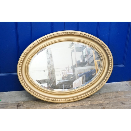 818 - An oval gilt painted mirror with ball decoration. Measuring 92cm x 70cm.