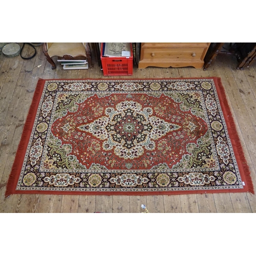 664 - A Burgundy Ground Central Medallion Wide Bordered Corner decorated Rug with Fringe. Measuring: 240cm... 