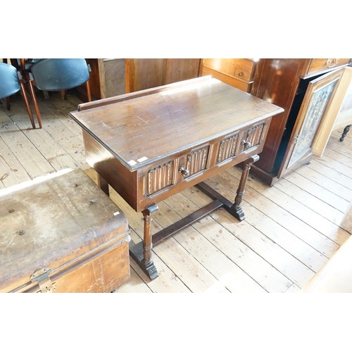 612 - A Reproduction Dark Oak Linen Fold Panel Fronted Side Table resting on turned legs & Two Drawers. Me... 