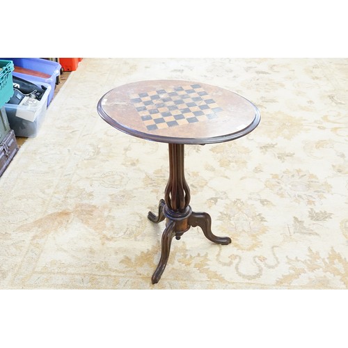 619 - A Victorian Walnut Veneered Oval Chess Top Table resting on a Tripod Base. Measuring: 61cms x 46cms ... 