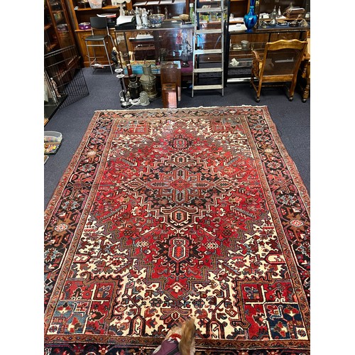 663A - A large red ground and beige rug. Measuring 242cm  x 339cm.