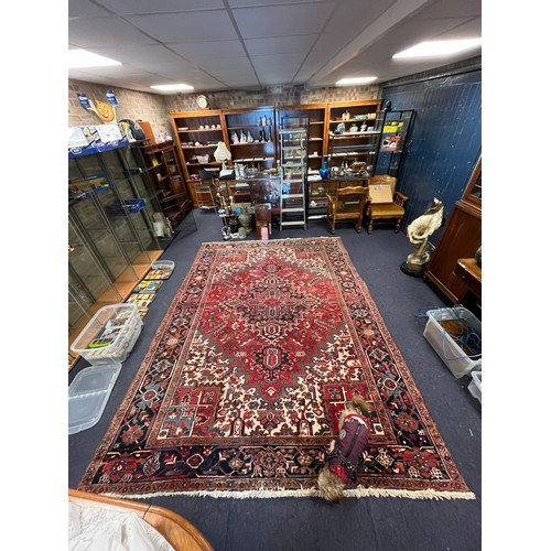 663A - A large red ground and beige rug. Measuring 242cm  x 339cm.