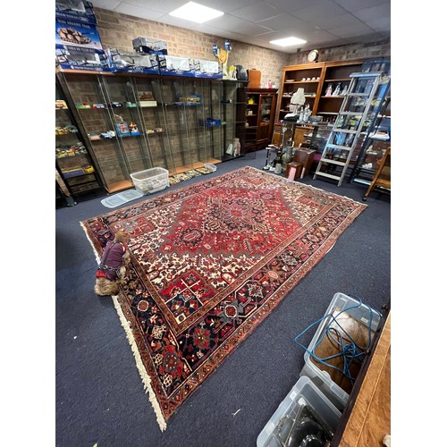 663A - A large red ground and beige rug. Measuring 242cm  x 339cm.