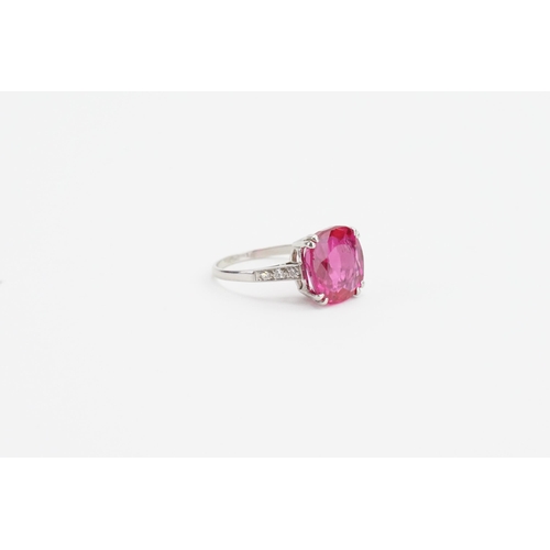 203 - A platinum cushion cut synthetic ruby ring, set with chip diamonds on the shoulders. Weight 4.5g.