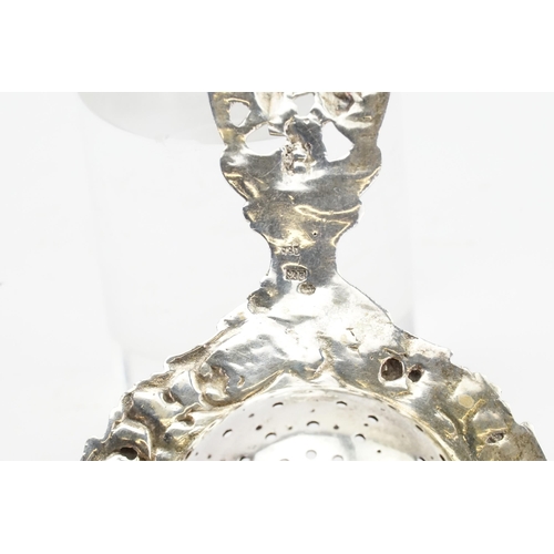 85 - A 830 marked silver cherub decorated tea strainer. Weight 51g.