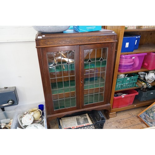 559 - A 1920s Oak Carved Top Bookcase fitted with Leaded Doors & standing on Pad Feet. Measuring.