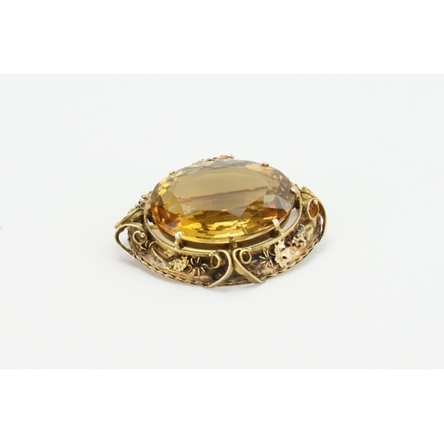 93 - A large oval cut Citrine brooch. Set in a gold coloured mount, with grape vine decoration. Size 33.1... 