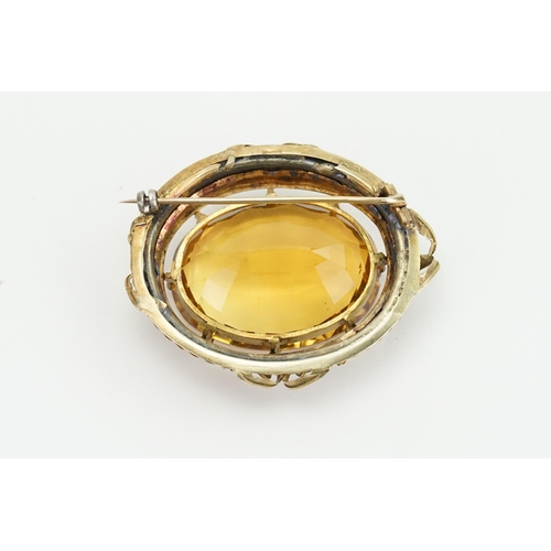 93 - A large oval cut Citrine brooch. Set in a gold coloured mount, with grape vine decoration. Size 33.1... 