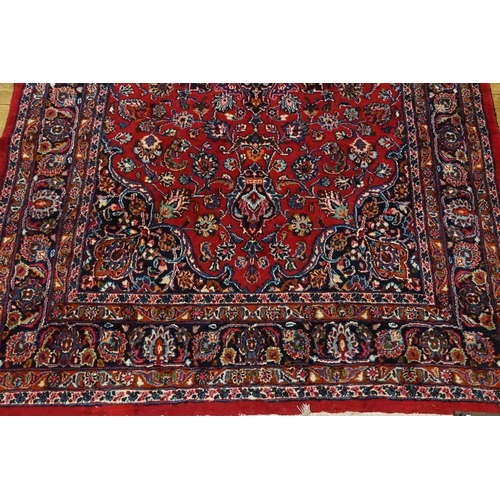 530 - A large red ground rug, with fringe decoration. Measuring 330cm x 202cm.