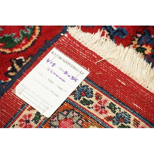 530 - A large red ground rug, with fringe decoration. Measuring 330cm x 202cm.