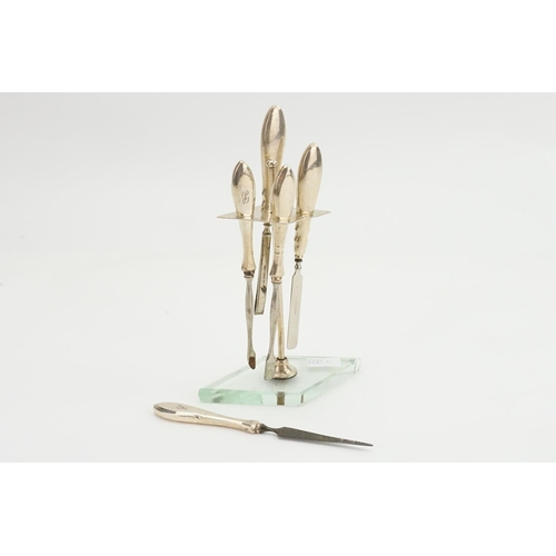 85 - A Silver Art Deco manicure set mounted on a glass stand.