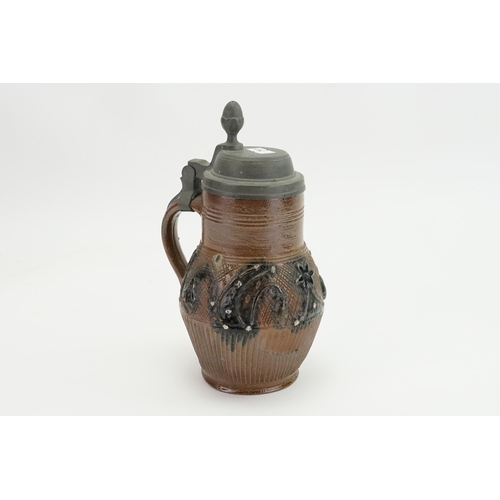 1002 - A German Stone Ware Beer Stein decorated with embossed flowers, a Pewter Lid & Thumb Piece.