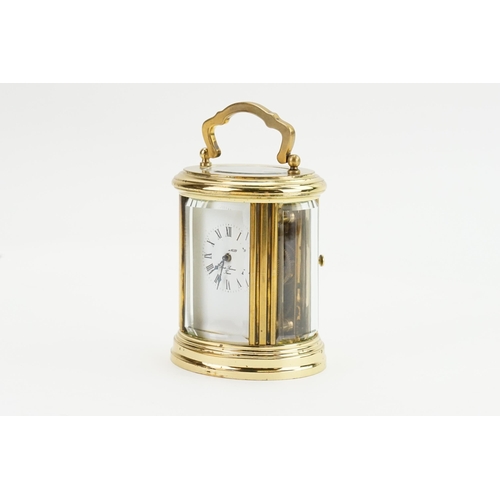 405 - A Modern Oval Brass Cased Carriage Clock with an enamelled face, Black Chaptering & Carrying Handle.... 